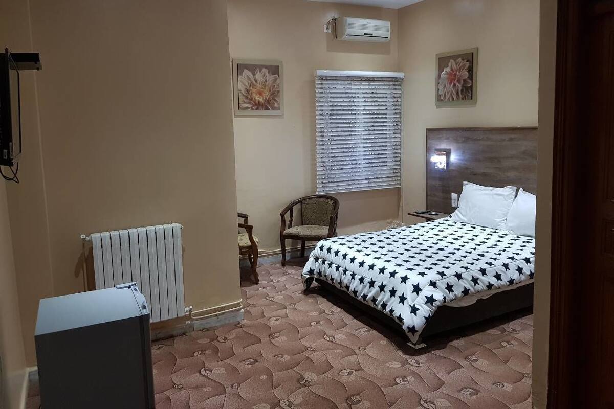 Quarto com cama, cadeira, radiador e aparelho de ar condicionado.