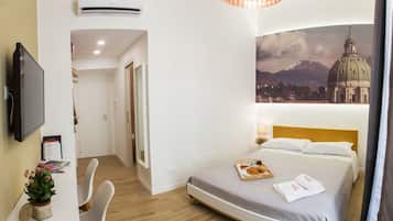 Hotelkamer met een bed, een bureau, een stoel, een televisie en een wandairconditioner.