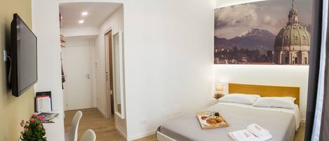 Une chambre d’hôtel équipée d’un lit, d’un bureau, d’une chaise, d’une télévision et d’un climatiseur fixé au mur.
