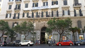 A historic building with a large arched entrance, multiple balconies, and a sign advertising a business. - Napolinn B&B (Naples)