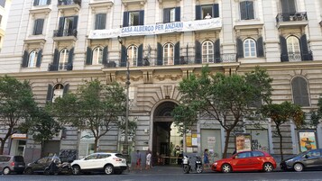 A historic building with a large arched entrance, multiple balconies, and a sign advertising a business.