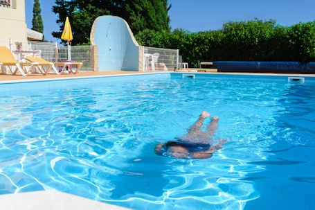 Una piscina al aire libre, sillones reclinables de piscina