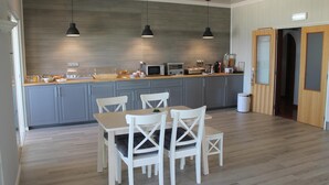 Une cuisine moderne avec des meubles gris, un plan de travail en bois et un coin repas avec des chaises blanches.