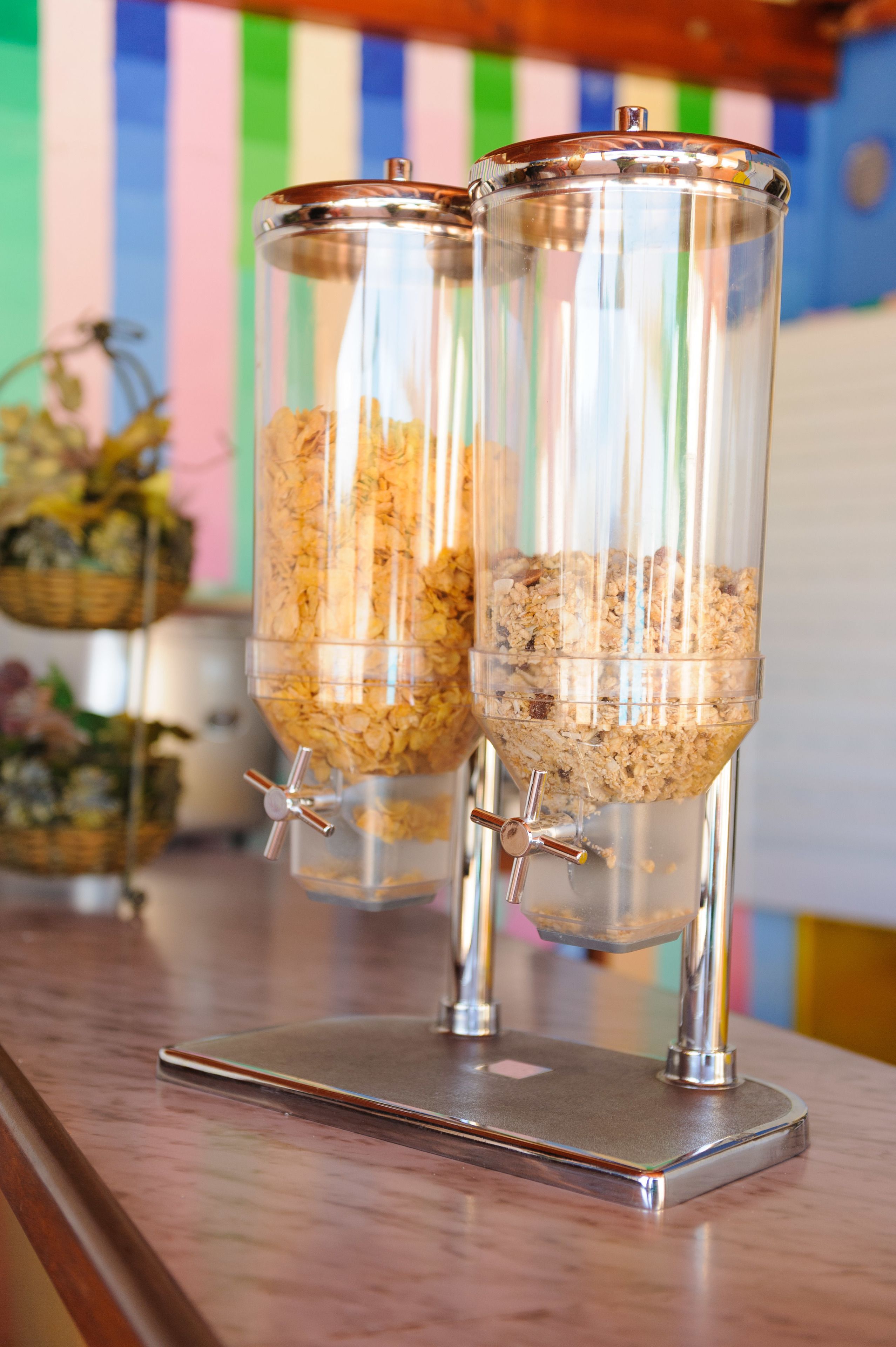 Two cylindrical dispensers filled with granola on a metallic stand.