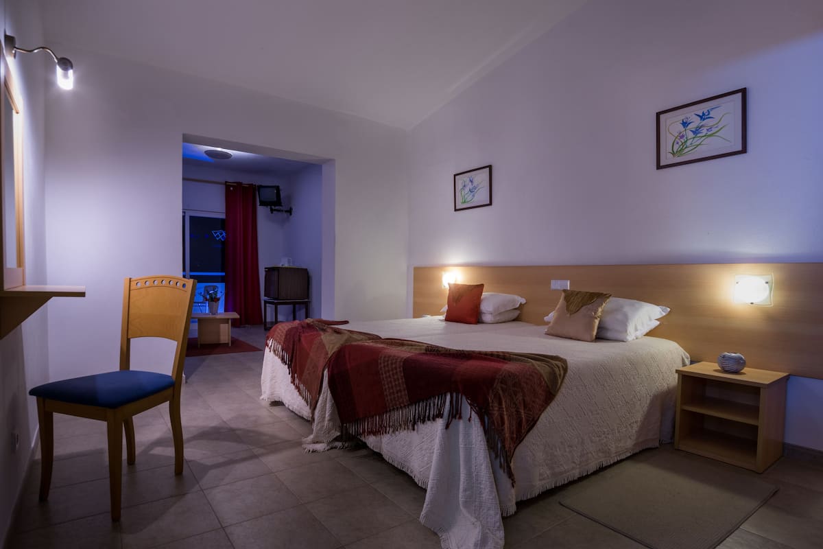 A bedroom with a bed, bedside tables, a chair, and a desk.
