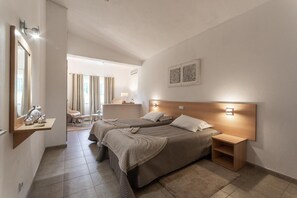 A modern hotel room with two beds, a sitting area, and a bathroom. - Welwitshia guest house (Lagoa)