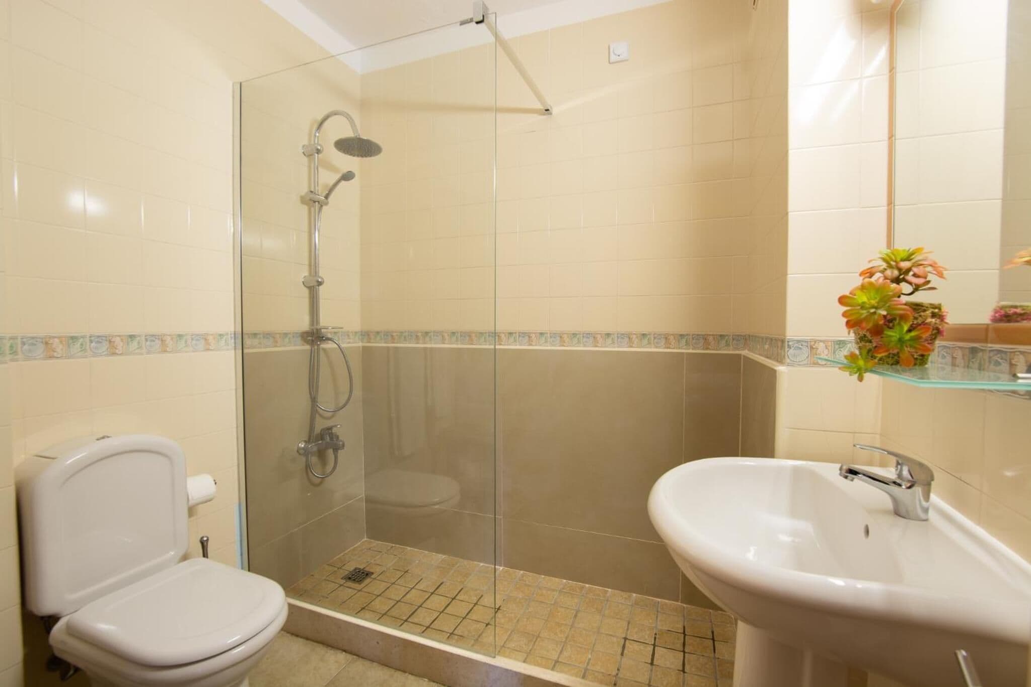 Un baño con ducha de mampara de vidrio, inodoro y lavabo.