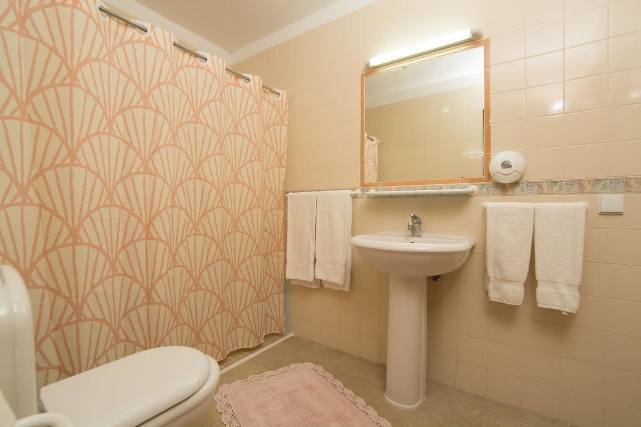 Un baño con inodoro, lavamanos y cortina de ducha.