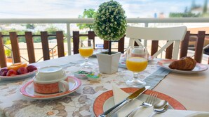 Une table de petit-déjeuner dressée avec des assiettes, des couverts et une petite plante en pot.