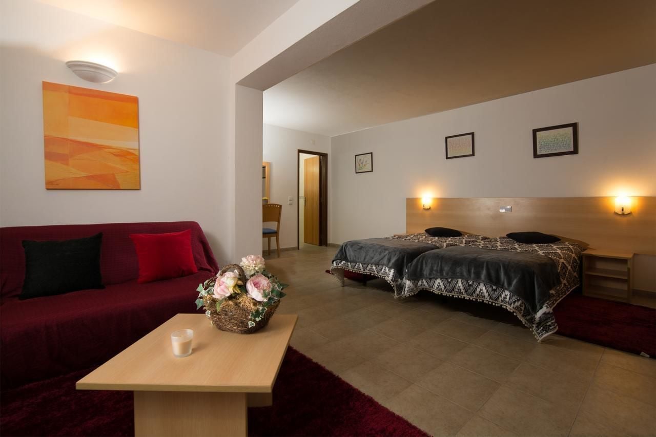 Une chambre d’hôtel moderne, équipée d’un lit, d’un canapé et d’une petite table sur laquelle est posé un vase de fleurs.