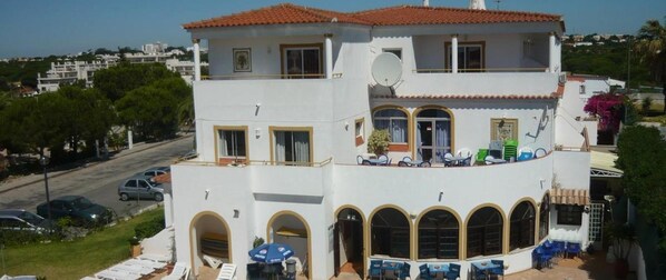 A two-story building with a balcony, arched windows, and a satellite dish.