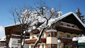 Un edificio tradicional de madera con tejado nevado y balcones, rodeado de nieve.
