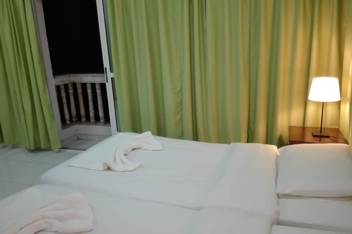 A hotel room with a bed, a nightstand with a lamp, and green curtains.