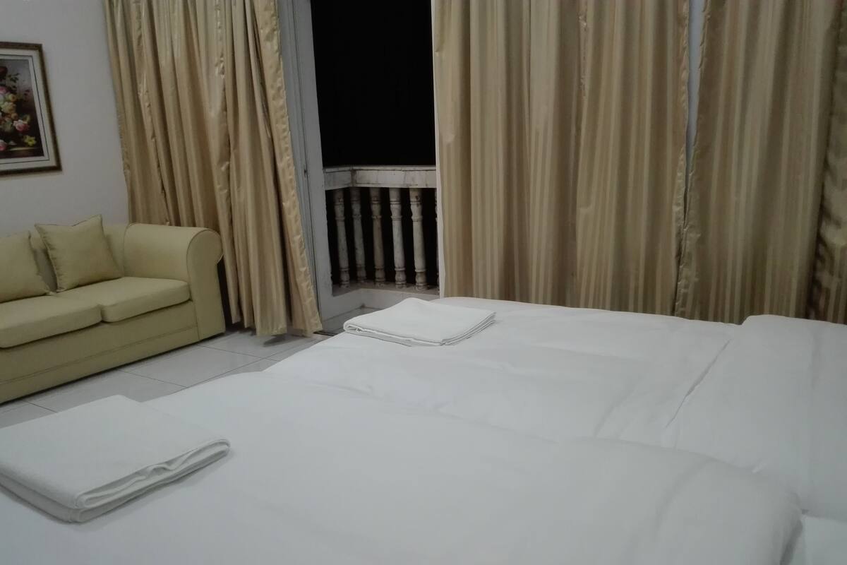 A hotel room with a bed, a sofa, and curtains.