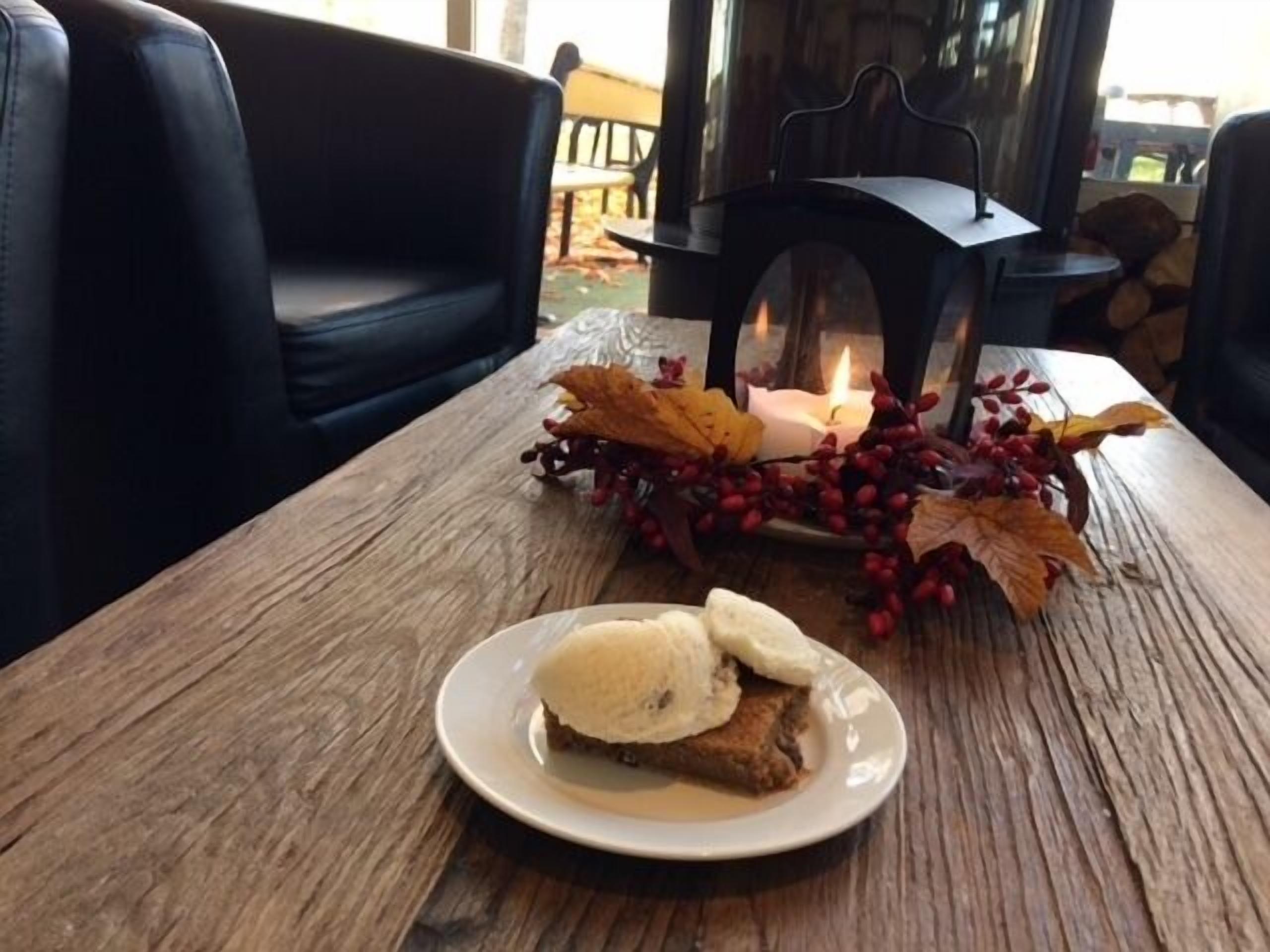 A wooden table with a plate of food, a candle, and autumn leaves.