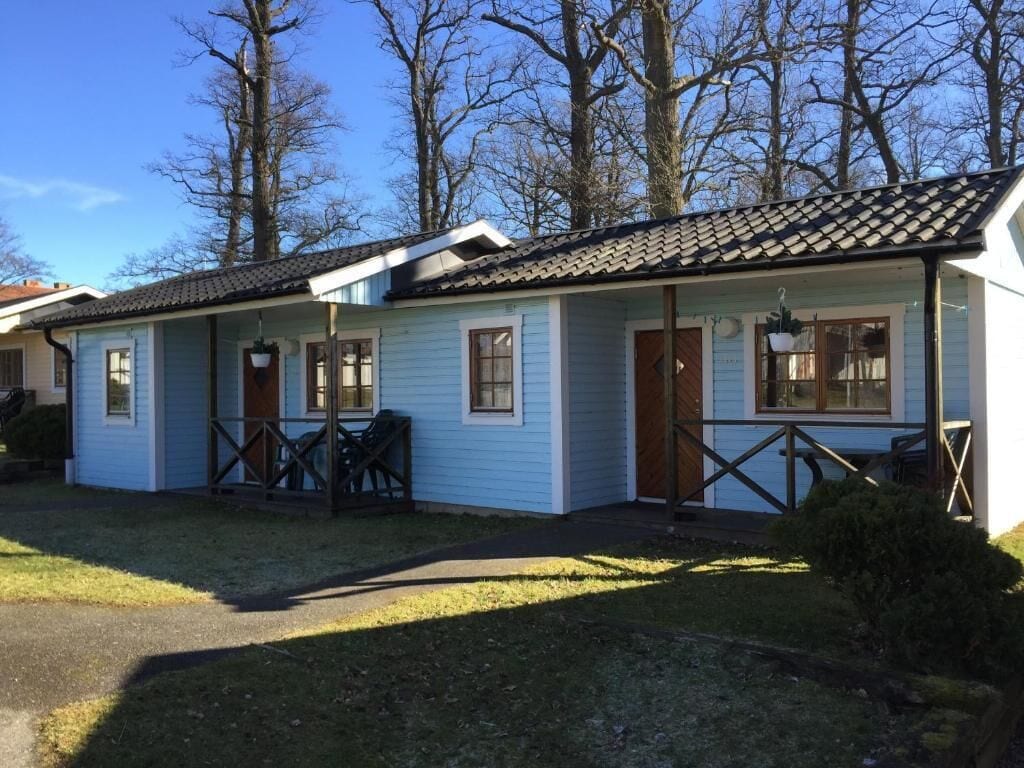 Une rangée de cabanes bleu clair, avec un toit en tuiles, des portes en bois et un petit porche.
