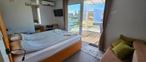 Una habitación de hotel moderna con cama, sofá, escritorio y televisor.