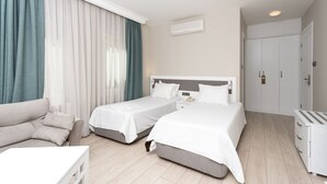 Een hotelkamer met twee bedden, een bank, een bureau en een kledingkast.