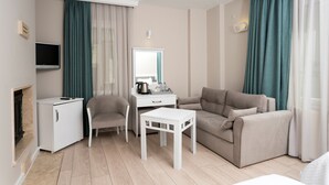 Een moderne woonkamer met een beige bank, een witte salontafel, een bureau met een spiegel, een televisie en een open haard.