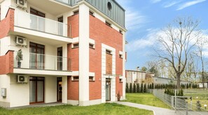 A multi-story residential building with a balcony, air conditioning units, and a well-maintained lawn. - Green Garden Residence (Kraków)