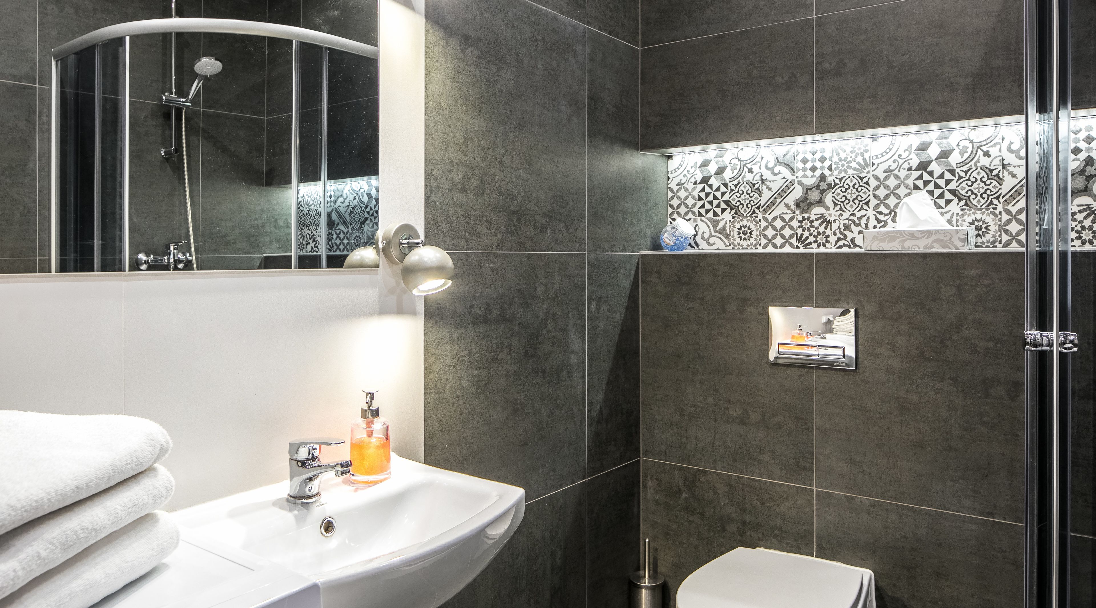 A modern bathroom with a curved shower, a sink with a mirror, and a toilet.