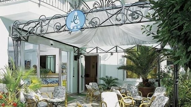 Un patio al aire libre con mobiliario de mimbre, piso a cuadros y plantas en macetas.