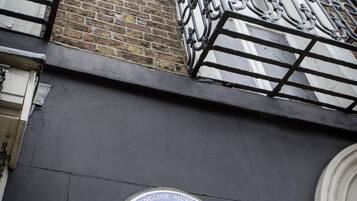 A blue plaque on a building wall with white trim.