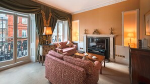 A living room with a fireplace, sofa, and television. - 10 Curzon Street Apartments by Mansley (London)
