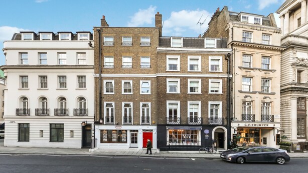 A row of multi-story buildings with a variety of architectural styles, including a white building with a red door and a brown brick building with a black awning. - 10 Curzon Street Apartments by Mansley (London)