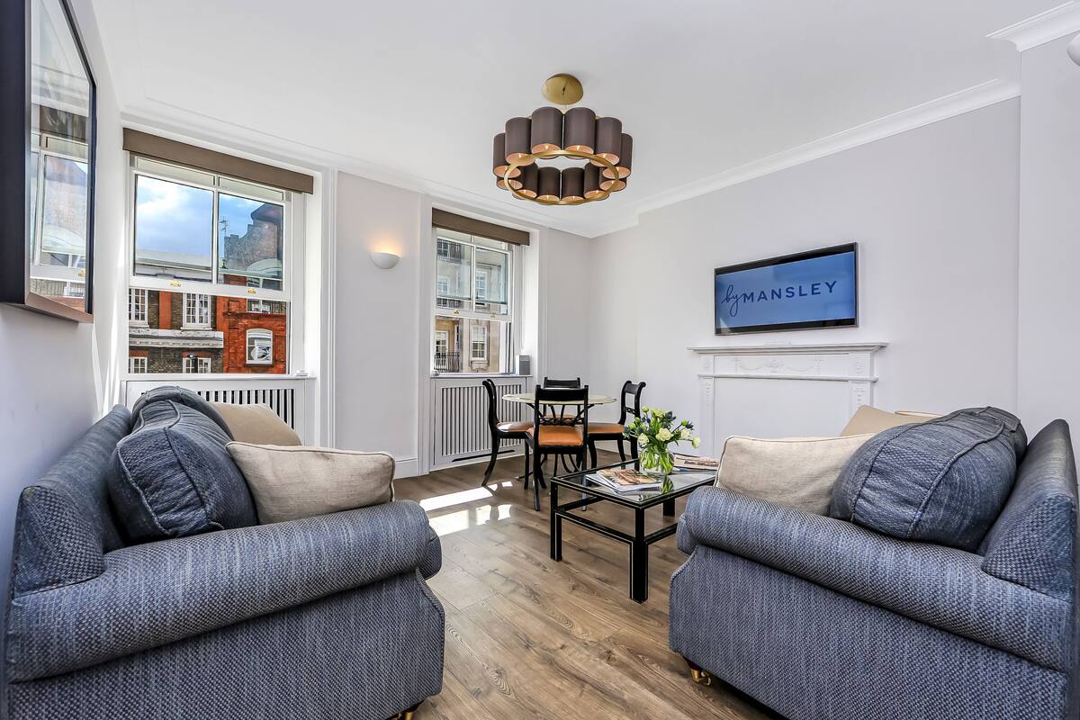 A modern living room with two grey sofas, a coffee table, and a chandelier.