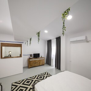 Une chambre à coucher moderne avec un lit, une commode en bois, un téléviseur et un miroir.