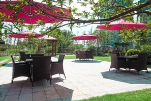 Eine Außenpatio-Terrasse mit Korbmöbeln und roten Sonnenschirmen.