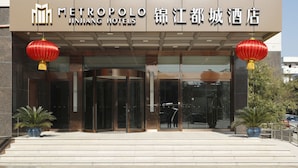 A hotel entrance with a modern facade, glass doors, and red lanterns. - Metropolo Nanjiang Baijia Lake (Nanjing)