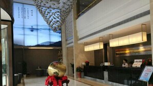 A hotel lobby with a reception desk, a large globe sculpture, and a view of mountains through the windows. - Yilong Hotel (Nanjing Southeast University Branch) (Nanjing)
