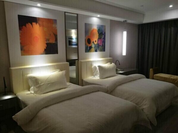 A hotel room with two beds, a nightstand, a desk, and a chair.