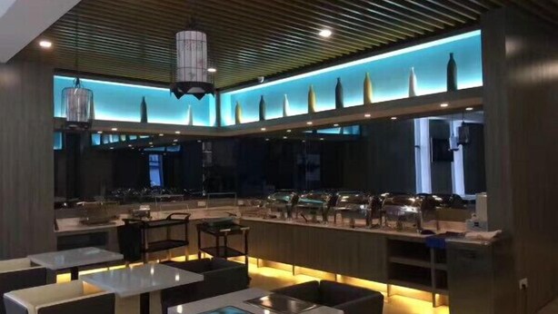 A modern restaurant interior with a central bar, seating areas, and a ceiling with linear lighting. - Yilong Hotel (Nanjing Southeast University Branch) (Nanjing)