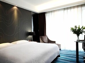 A modern hotel room with a large bed, a desk, a chair, and a plant. - Metropolo Fuzhou Taijiang (Fuzhou)