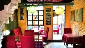 Un restaurante con sillas y mesas rojas, un muro de ladrillo y farolillos de papel colgantes.