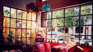 Una habitación con ventanas amplias, un sofá rojo y una mesa con mantel.