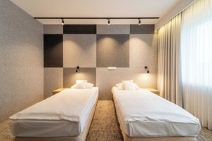 Una habitación de hotel con dos camas individuales, un diseño de pared a cuadros y una ventana con cortinas.