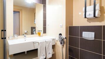 A modern bathroom with a large mirror, a white sink, a towel rack, and a toilet.