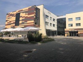 Un hotel moderno con una fachada distintiva, zona de estar al aire libre y un patio bien cuidado.