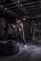 Un gimnasio con equipo de ejercicio, incluyendo un neumático, una barra y un banco de pesas.