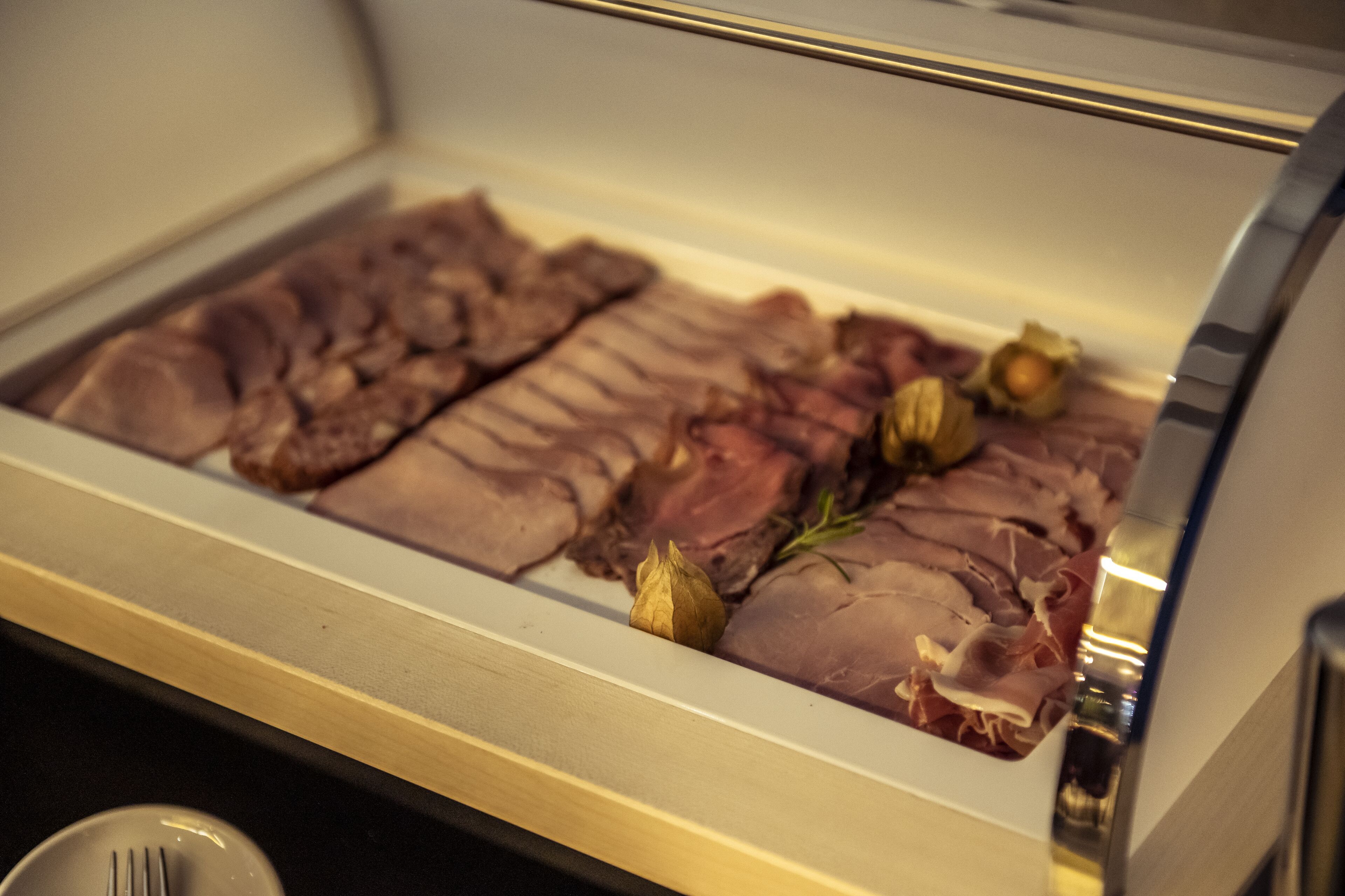 A display case with various cuts of meat and herbs.