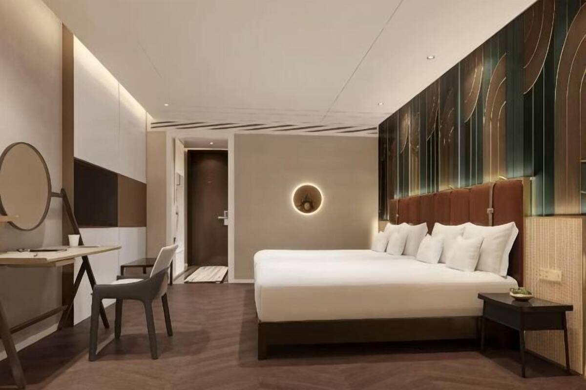 A modern hotel room with a large bed, a desk, and a chair.