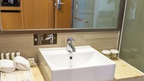 Une salle de bain avec un lavabo blanc, un miroir et un porte-serviettes.
