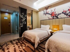 A hotel room with two beds, a large mirror, a floral wall decoration, and a carpet with a floral pattern.