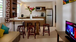 Una cocina moderna con una isla central, taburetes de bar, microondas y refrigerador.