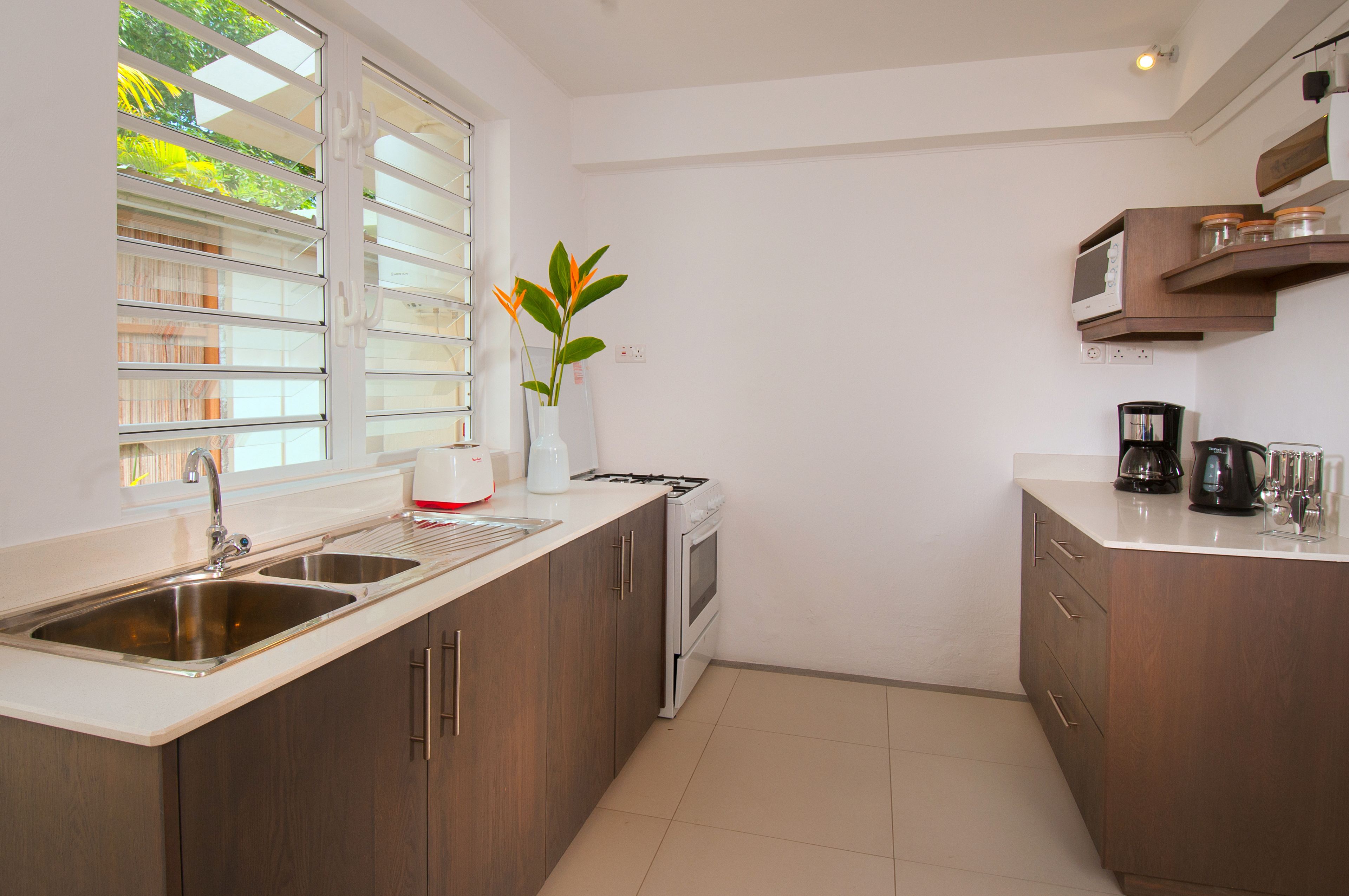 A modern kitchen with stainless steel sinks, a white stove, and wooden cabinets.