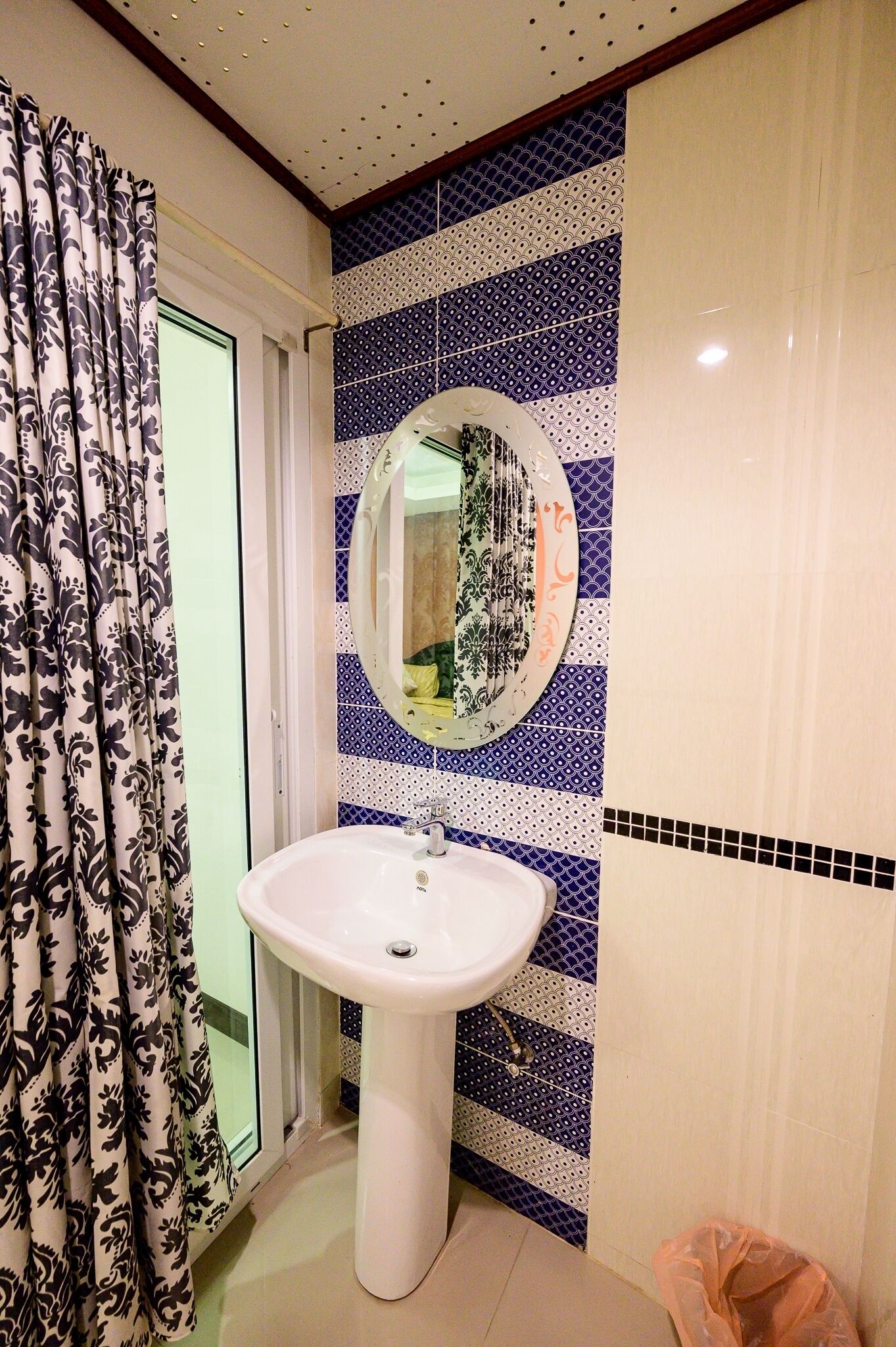 Un baño con un lavabo blanco, un espejo y baldosas estampadas.